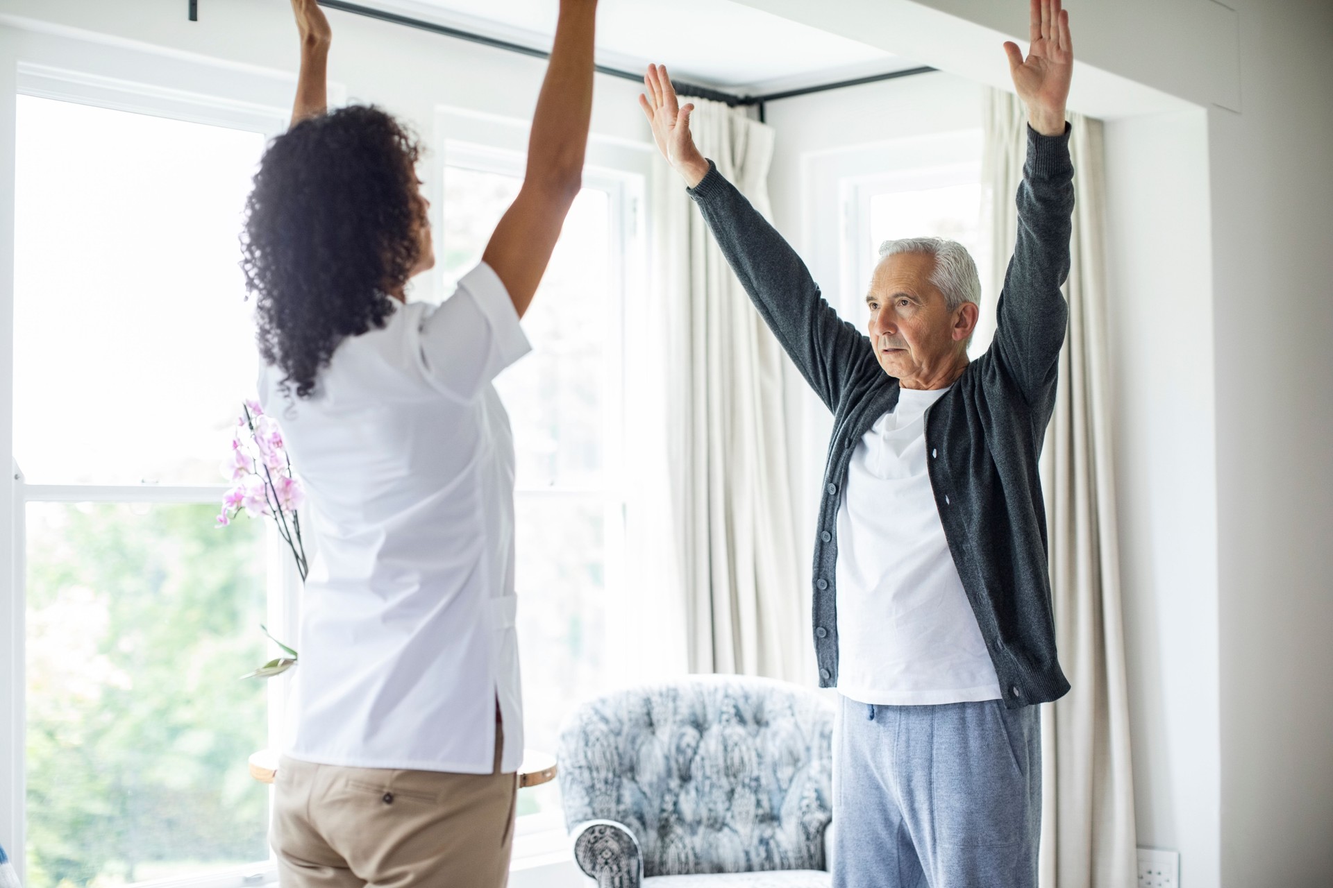 Nurse and patient exercising with arms raised